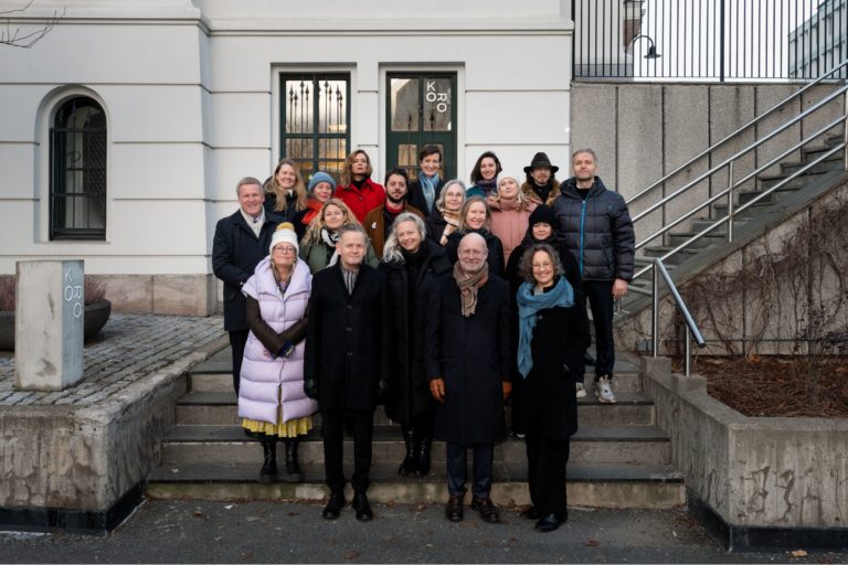 En gruppe på 20 mennesker poserer utenfor inngangsdøren til KORO.